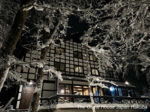 un edificio con árboles nevados delante de él en The Guest House Japan Hakuba en Hakuba