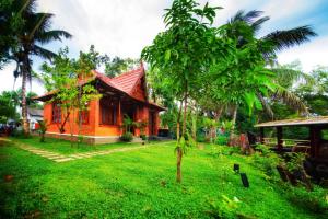 a small house in a yard with a green field at Little Chembaka in Kumarakom