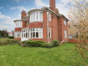 a large red brick house with a grass yard at Seawinds in Colwyn Bay