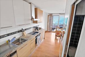 a kitchen with white cabinets and a sink and a table at Appartement chaleureux avec une magnifique vue in Crans-Montana +13 photos