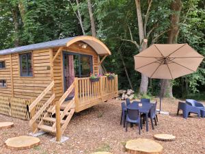 Cabaña de madera con mesa y sombrilla en Le Chalet Montégut, en Moulins