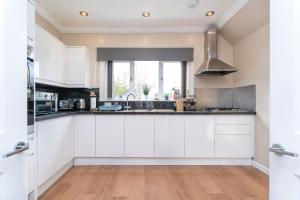 a kitchen with white cabinets and a sink at NEW Four Bedroom House - all rooms ensuite in Stirling