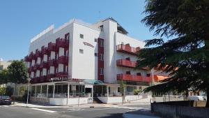 un grande edificio bianco con un'auto parcheggiata di fronte di Hotel Vienna a Lignano Sabbiadoro