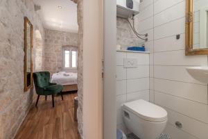 a bathroom with a toilet and a sink and a bedroom at Residence Providenca in Trogir