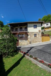 a house on the side of a road with flowers in front at Apartamentos 'Los Balcones de Nieda 2' in Cangas de Onís