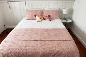 a pink and white bed with a pink blanket and pillows at Grandma's Attic in Lakewood