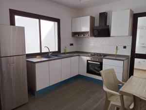 a kitchen with white cabinets and a sink and a refrigerator at Superbe Appartement in Sousse
