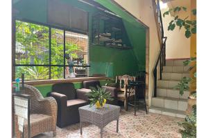 OYO 876 Escurel Inn Boracay في بوراكاي: غرفة بها كراسي وطاولات وجدار أخضر