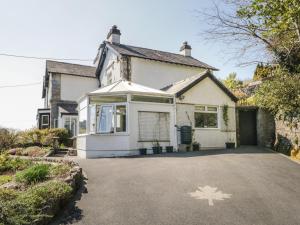 una casa blanca con una hoja de arce pintada en la entrada en Yewbarrow Cottage, en Grange-over-Sands