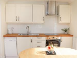 a kitchen with white cabinets and a bowl of fruit on a table at Copse View in Lincoln