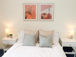 a bedroom with a white bed with pillows and paintings on the wall at Copse View in Lincoln