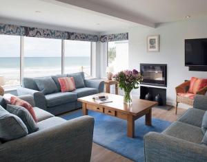 a living room with couches and a table and a television at The White House in Polzeath