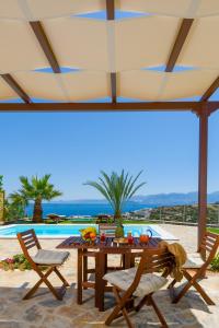 a patio with a table and chairs and a pool at Villa Calypso Elounda in Elounda