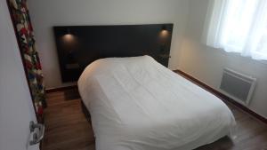 ein Schlafzimmer mit einem weißen Bett mit einem schwarzen Kopfteil in der Unterkunft Résidence de Tourisme LE VENDAHAUT in Lapleau