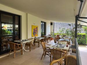 een restaurant met tafels, stoelen en ramen bij Hotel Marina in Torri del Benaco