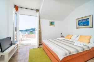 a bedroom with a bed and a tv and a balcony at Apartments Villa Cerjak in Slano