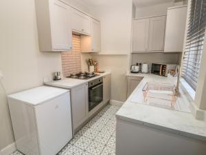 a kitchen with white cabinets and a stove top oven at Calder Cottage in Sowerby Bridge