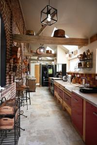 une grande cuisine avec des placards en bois et un mur en briques dans l'établissement Le Domaine des Agapanthes - SPA, à Épreville