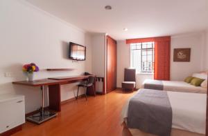 a hotel room with a desk and a bed at ApartaSuites & Hotel Bogota Plaza 36 in Bogotá