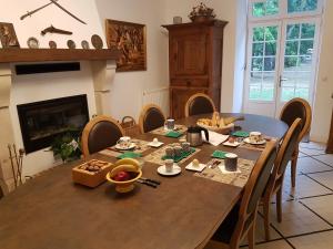 a dining room with a table and chairs and a fireplace at l'Airial de Larroque in Soustons