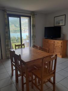 een eetkamer met een houten tafel en een groot raam bij SAVINES LE LAC APPARTEMENT VUE SUR LE LAC in Savines