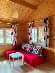 a red couch in a wooden room with a table at LIDO - domy letniskowe z klimatyzacją in Krynica Morska