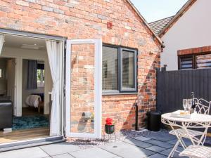 an open door to a brick house with a patio at Oakleigh in Llanymynech