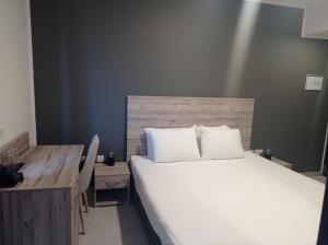 a bedroom with a white bed and a desk and a bed sidx sidx at Hotel VIU57 in Mellieħa