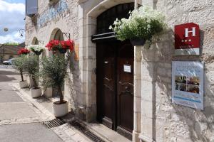 um edifício com uma porta com vasos de plantas sobre ele em Le Pavillon Saint-Martin em Souillac