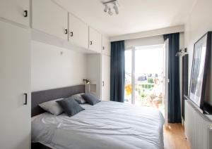 - une chambre avec un grand lit blanc et une fenêtre dans l'établissement Endless Sea View, à Knokke-Heist