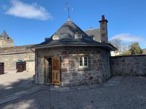 un pequeño edificio de piedra con techo en The Hen House en Beauly