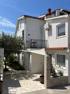 a white house with a balcony and a patio at Mozgan Apartments in Piran