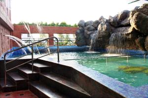 a swimming pool with a waterfall and stairs in a zoo at Parklane Hotel in Mysore