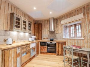 cocina con armarios de madera, mesa y fogones en The Hen House, en Beauly