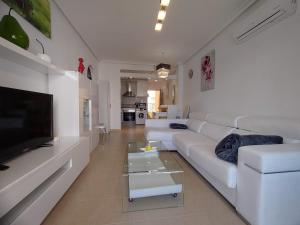 - un salon avec un canapé blanc et une télévision dans l'établissement Lovely apartment with pool view, à Orihuela