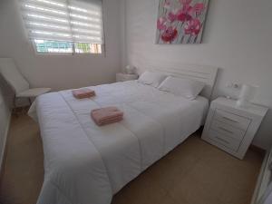 een slaapkamer met een wit bed en 2 handdoeken bij Lovely apartment with pool view in Orihuela