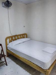 1 cama en una habitación con una pared blanca en Alquiler de habitaciones BAY HOUSE HOSTEL, en Salinas