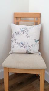 a pillow on a wooden chair with a bird pattern at Solheimir at Strathmore Golf Course in Blairgowrie