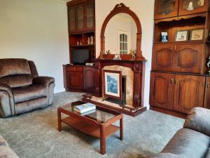 uma sala de estar com lareira e um sofá e uma cadeira em 4 Bedroom, 15 min to Limerick city Quiet Retreat. em Limerick