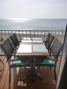 uma mesa e cadeiras numa varanda com praia em Medi Playa primera linea con piscina em Calpe