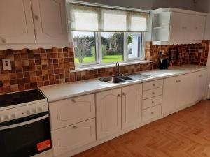 a kitchen with white cabinets and a sink and a window at 4 Bedroom, 15 min to Limerick city Quiet Retreat. in Limerick