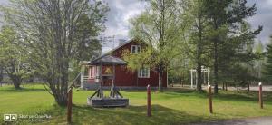 una casa roja con un parque infantil delante de ella en Raate Guest House en Suomussalmi