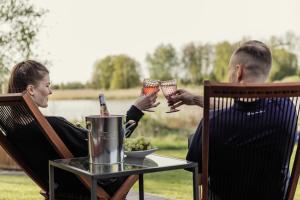 mężczyzna i kobieta siedzący przy stole z kieliszkami do wina w obiekcie Dragonfly Lake House εïз w mieście Limbaži