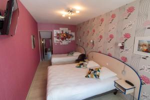 a room with two beds and a pink wall at LOGIS Le CANTAREL 