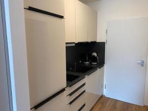 a small kitchen with white cabinets and a sink at Haus München in Bad Griesbach