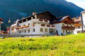 a large building on a hill with a green field at Hotel Kristall B&B in Ischgl
