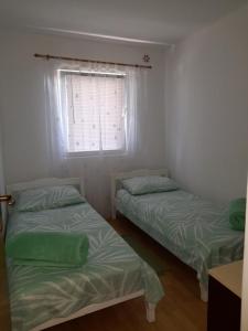 two beds in a room with a window at Apartmani Pleša in Vir