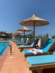 a row of lounge chairs with umbrellas next to a swimming pool at Saradari Beach Hotel - Adults Only in Hersonissos