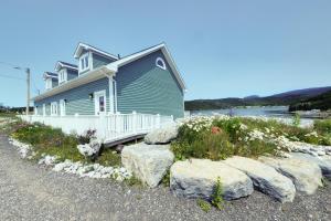 a blue house with rocks in front of it at Gros Morne BaseCamp in Norris Point
