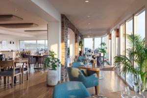 a restaurant with blue chairs and tables and windows at The Lewinnick Lodge in Newquay